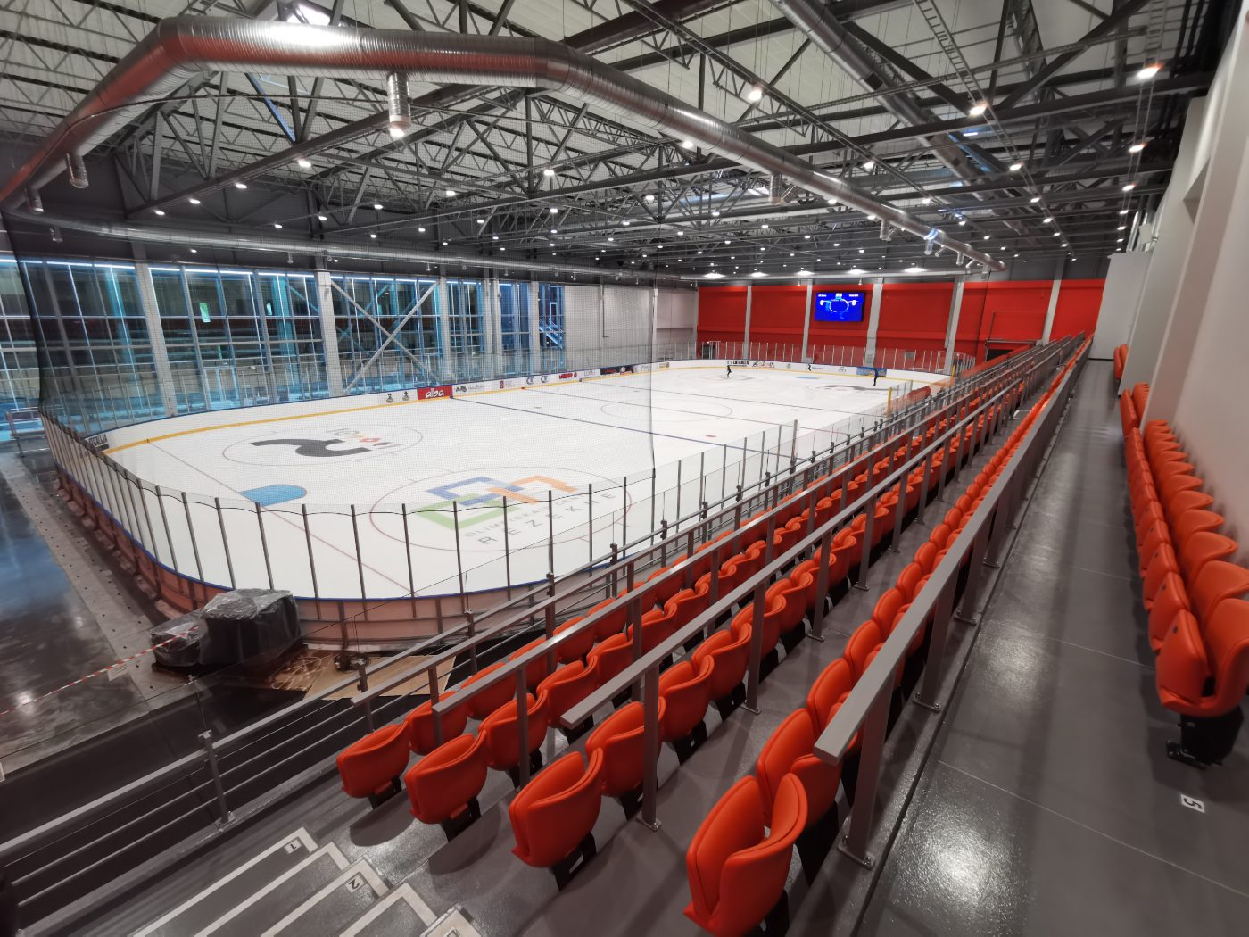 Indoor rink overview with orange spectator seating