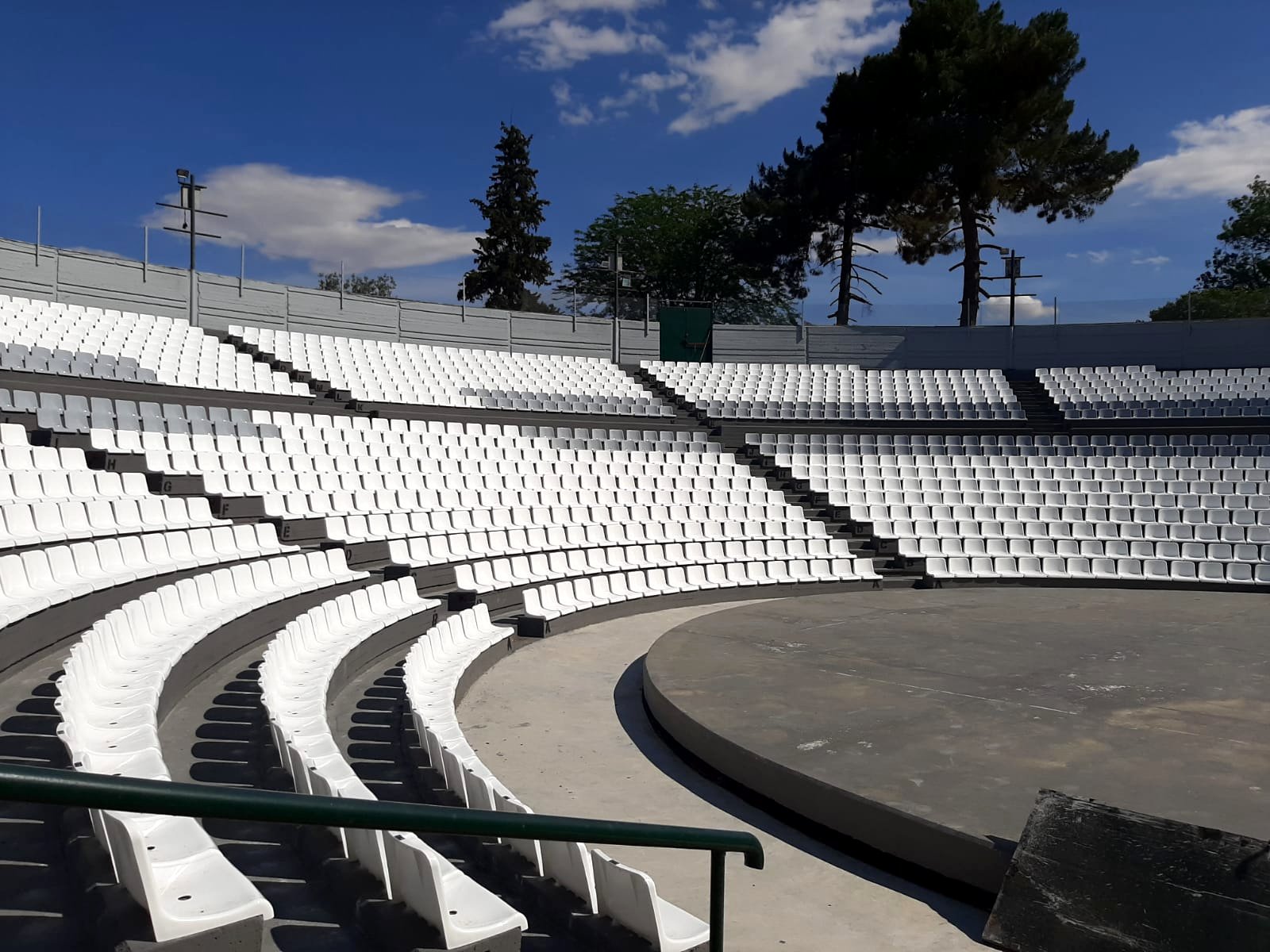 White tiered amphitheatre seating outdoors under a blue sky